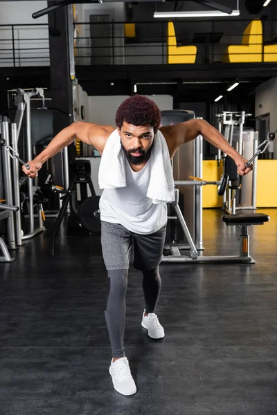 Barbudo afroamericano hombre ejercitando en brazo extensión entrenamiento máquina - foto de stock