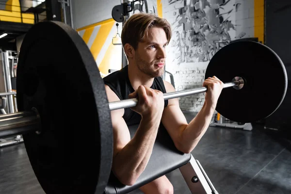 Jeune homme sportif faisant de l'exercice avec haltère dans un centre sportif — Photo de stock