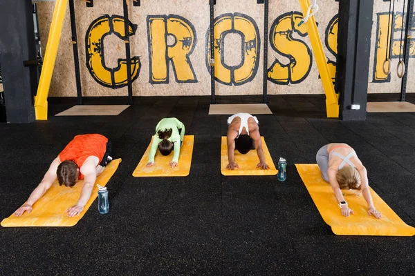 Entrenamiento en grupo deportivo en pose de flexión hacia adelante sentada en colchonetas de fitness - foto de stock