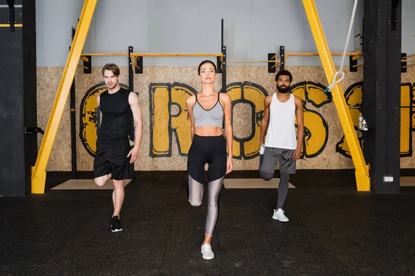 Vue complète de personnes sportives multiethniques s'entraînant en salle de gym — Photo de stock