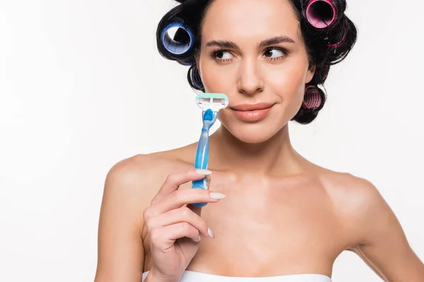 Smiling young woman in curlers holding razor near face isolated on white — Stock Photo