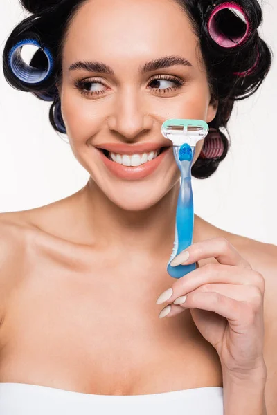 Positive young woman in curlers holding razor near face isolated on white — Stock Photo