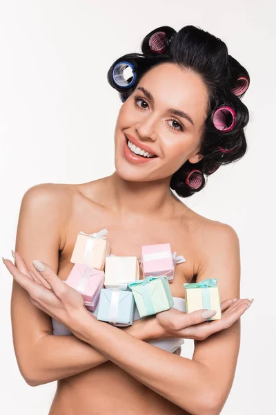Positive young woman in curlers holding small gift boxes in crossed arms isolated on white — Stock Photo