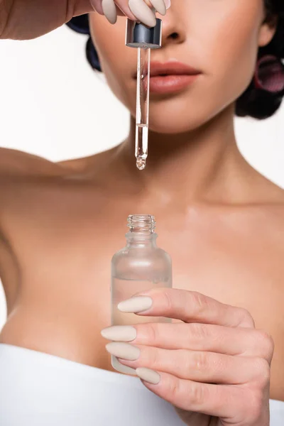 Vista parcial de una mujer joven sosteniendo botella de suero y pipeta con gota en las manos aisladas en blanco - foto de stock