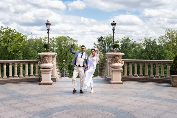 Emocionados recién casados mostrando sí gesto en el parque - foto de stock