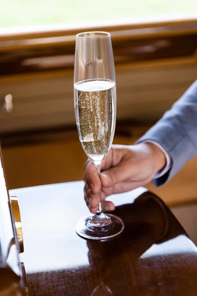 Vista cortada de copo de champanhe na mão do noivo em carro retro — Fotografia de Stock