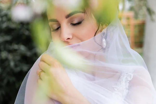 Portrait de jeune mariée tenant un voile flou à l'extérieur — Photo de stock