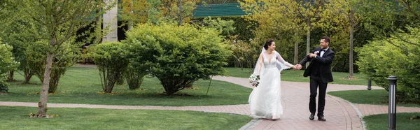 Esposo sorridente apontando com o dedo para noiva no parque, banner — Fotografia de Stock