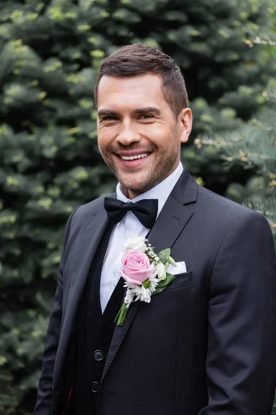 Groom en costume souriant à la caméra dans le parc — Photo de stock