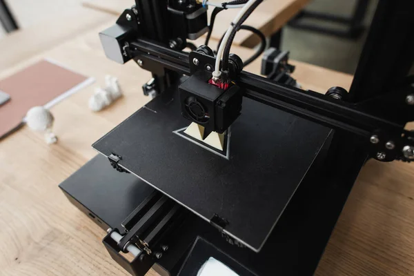 High angle view of 3D printer creating plastic model on table near blurred figures in office — Stock Photo