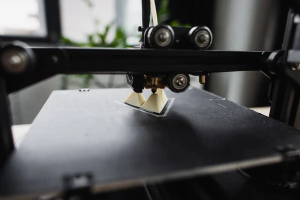 Vue rapprochée de l'imprimante 3D créant un modèle en plastique dans un bureau moderne — Photo de stock