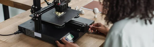 Vista parcial del joven diseñador que trabaja con la impresora 3D en la oficina moderna, banner - foto de stock