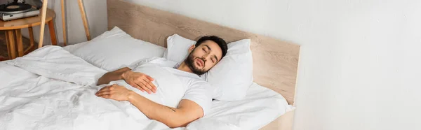 Jeune homme en t-shirt blanc dormant sur le lit, bannière — Photo de stock