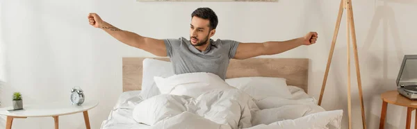 Young man stretching on bed in morning, banner — Stock Photo