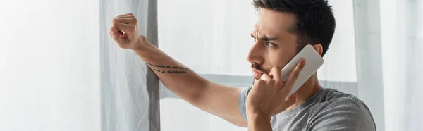 Side view of young man talking on smartphone near window, banner — Stock Photo