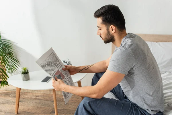 Vista lateral do homem no pijama ler jornal na cama — Fotografia de Stock