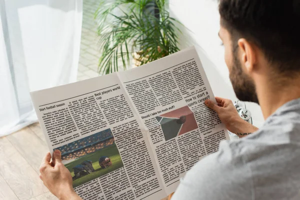 Hombre borroso leyendo noticias deportivas en casa - foto de stock