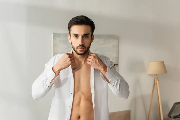 Mann blickt in Kamera und trägt zu Hause weißes Hemd — Stockfoto