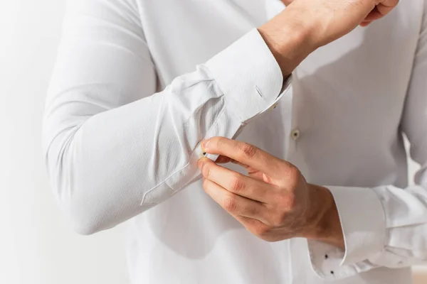 Cropped view of man buttoning sleeve of white shirt — Stock Photo