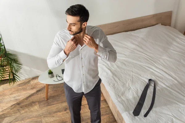 Visão aérea do empresário vestindo camisa perto de gravata na cama no quarto em casa — Fotografia de Stock