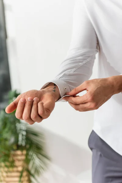 Cropped view of blurred man buttoning shirt at home — Stock Photo