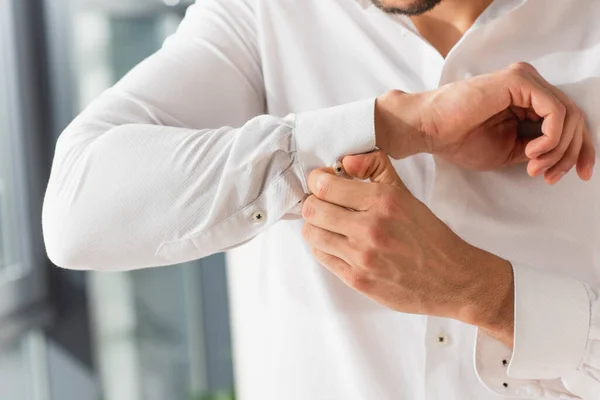 Cropped view of man buttoning up sleeve of shirt — Stock Photo