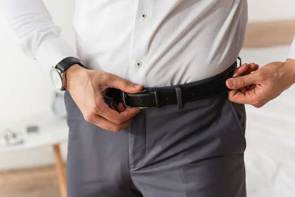 Cropped view of businessman adjusting waist belt at home — Stock Photo