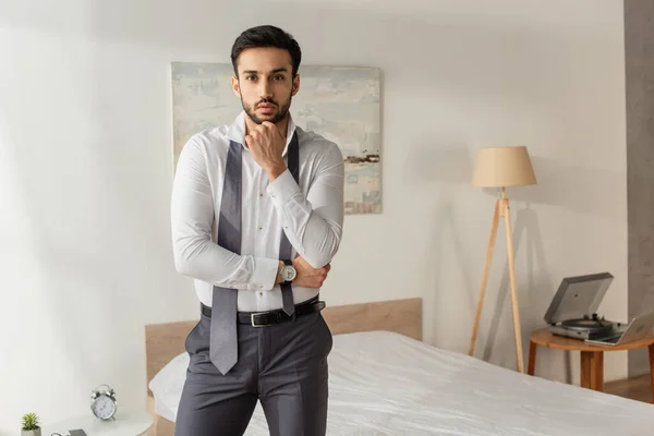 Businessman in shirt and tie looking at camera in bedroom — Stock Photo