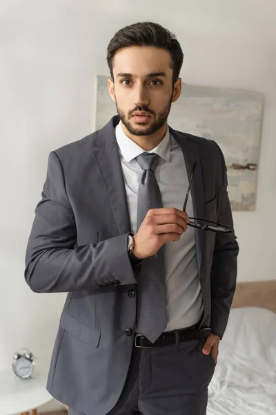 Joven hombre de negocios con gafas y mirando a la cámara en el dormitorio - foto de stock