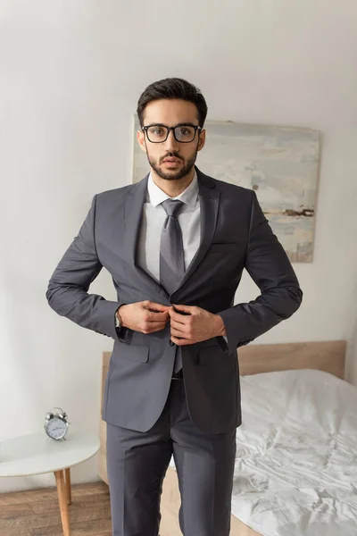 Bearded businessman buttoning jacket in bedroom at home — Stock Photo