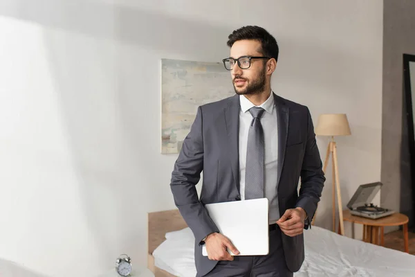 Young businessman with laptop standing in bedroom at home — Stock Photo