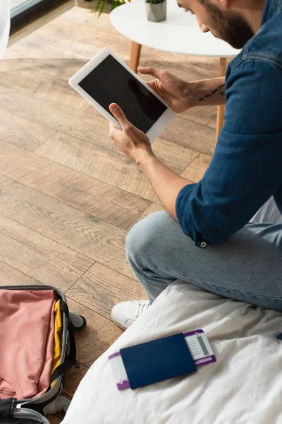 Koffer in der Nähe von Touristen mit digitalem Tablet in der Nähe Pass mit Flugticket auf dem Bett — Stockfoto
