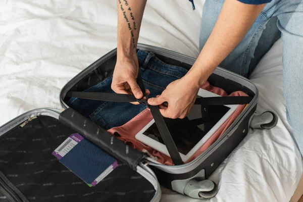 Ausgeschnittene Ansicht der Touristenverriegelung von Koffer mit digitalem Tablet und Pass auf dem Bett — Stockfoto