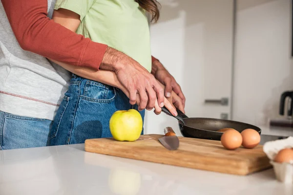 Cropped view of couple preparing pancakes near apple and eggs on cutting board — Stock Photo