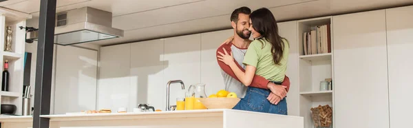 Positives Paar umarmt sich beim Frühstück und Orangensaft, Banner — Stockfoto