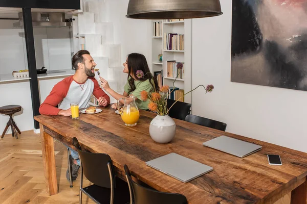 Vista laterale della donna sorridente che alimenta il fidanzato con pancake — Foto stock