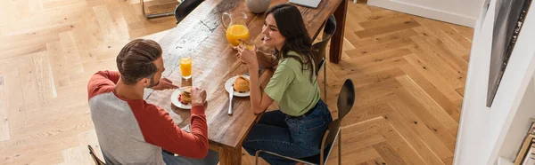Vista aérea de la joven pareja hablando cerca del desayuno en la mesa, pancarta - foto de stock