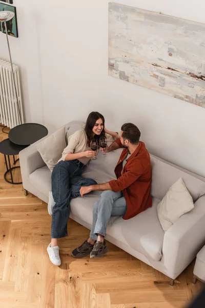 Blick aus der Vogelperspektive auf ein junges Paar, das mit Wein auf der Couch klingelt — Stockfoto