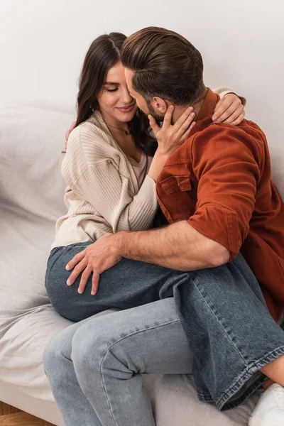 Homem beijando namorada no sofá em casa — Fotografia de Stock