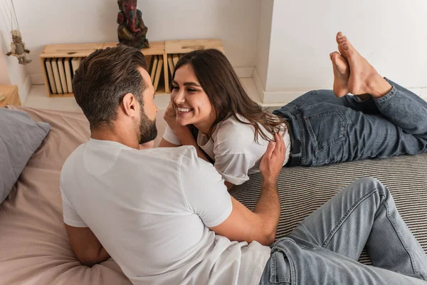 Man hugging cheerful girlfriend on bed — Stock Photo