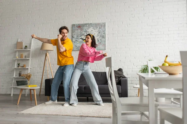 Sonriente joven pareja en ropa casual bailando en moderno loft - foto de stock