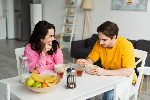 Sorridente giovane coppia seduta a tavola e fare colazione in soggiorno — Foto stock