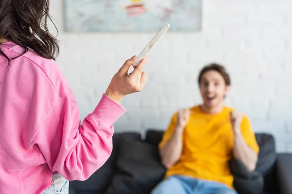 Young woman holding pregnancy test near blurred excited boyfriend at home — Stock Photo