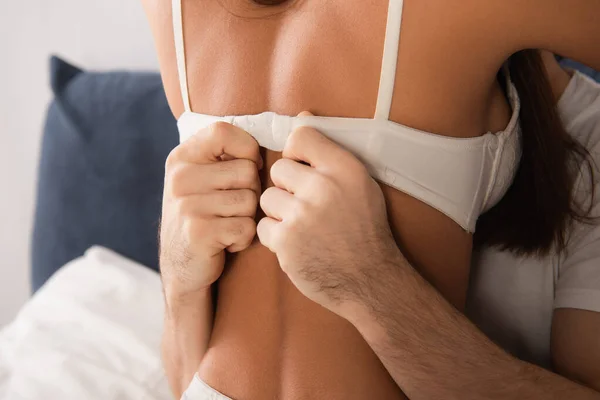 Recortado vista del hombre desabrochado sujetador de la mujer seductora — Stock Photo