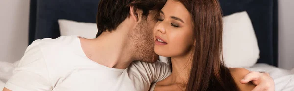 Молодой человек целует сексуальную брюнетку женщина в спальне, баннер — стоковое фото