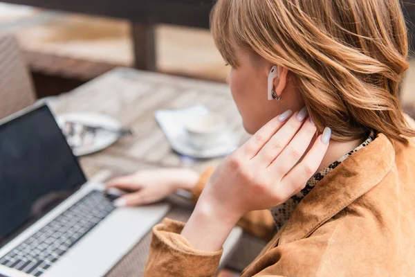 Young woman in earphone using blurred laptop on terrace — Stock Photo