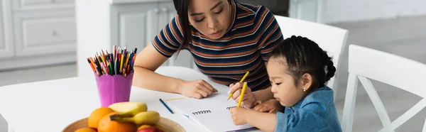 Asiático madre y niño dibujo cerca de frutas en cocina, bandera - foto de stock