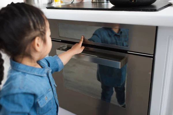 Blurred asian kid touching oven display in kitchen — Stock Photo