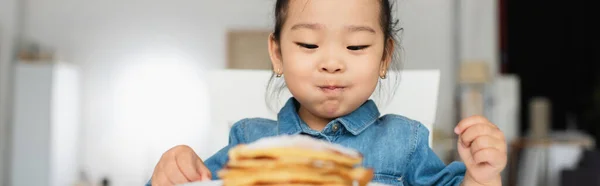 Азиатская малышка смотрит на размытые блины, плакат — стоковое фото