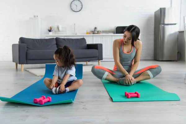 Asian mother and kid training near dumbbells at home — Stock Photo